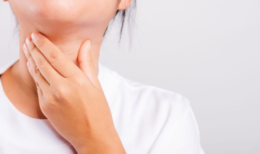 Woman checking her throat, representing thyroid health